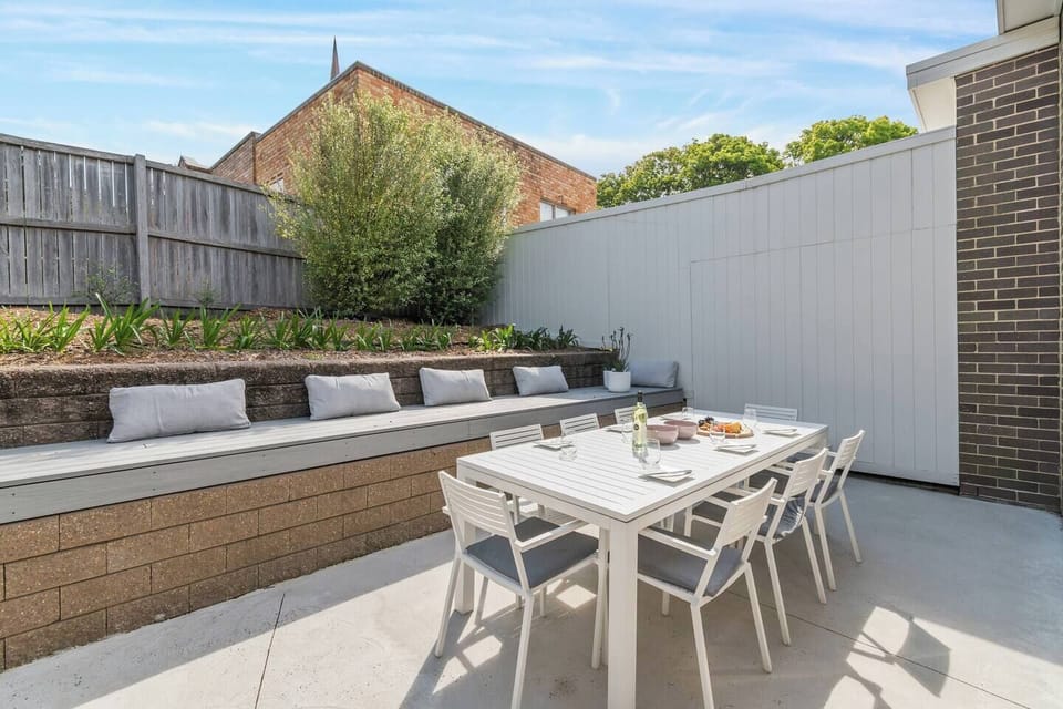Dine alfresco on the sun-drenched patio, featuring a full outdoor dining setting, cushioned bench seating, and lush greenery—ideal for long lunches or late-night conversations under open skies.