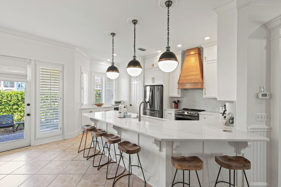 Your stunning white kitchen awaits with marble countertops, designer pendant lights, and a spacious island perfect for morning coffee or evening gatherings.