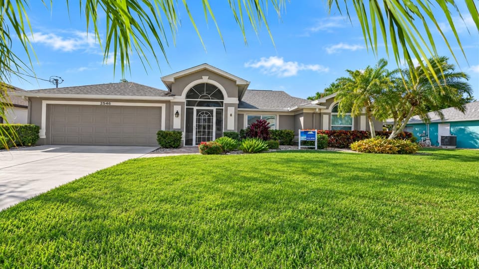 Palm trees and a neatly landscaped front lawn frame the villa's welcoming entrance.