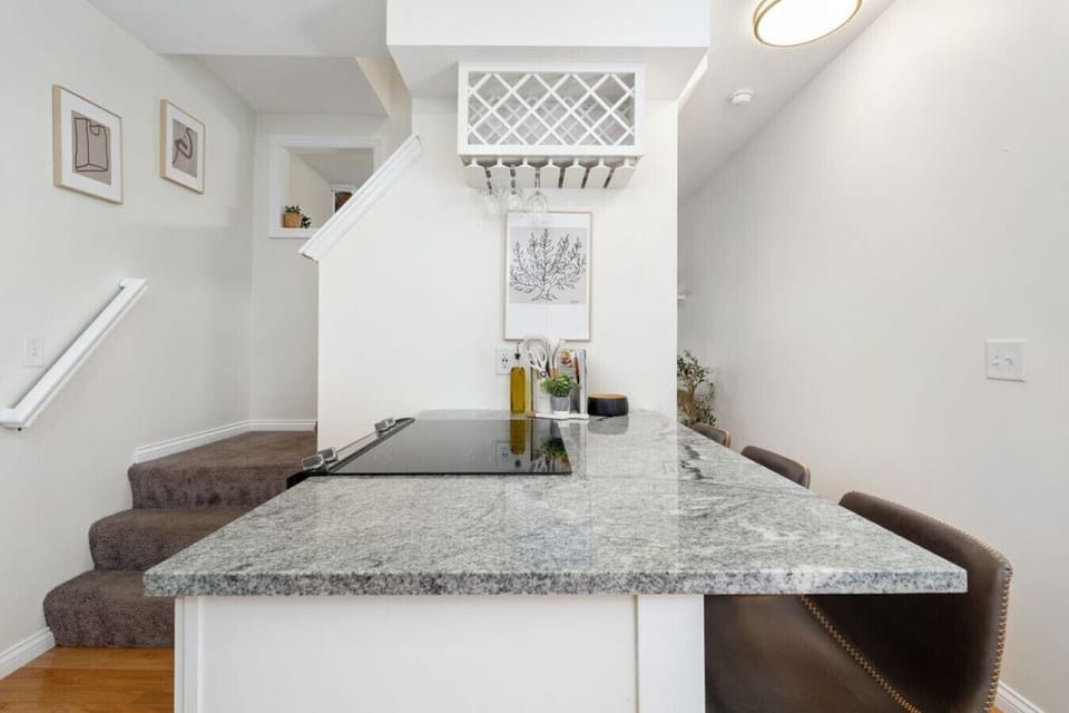 Quartz countertop peninsula with bar seating and stairs to the upper level.