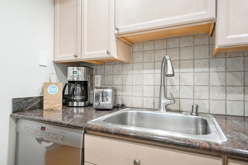 Kitchen counter with coffee maker, toaster, and stainless-steel sink.