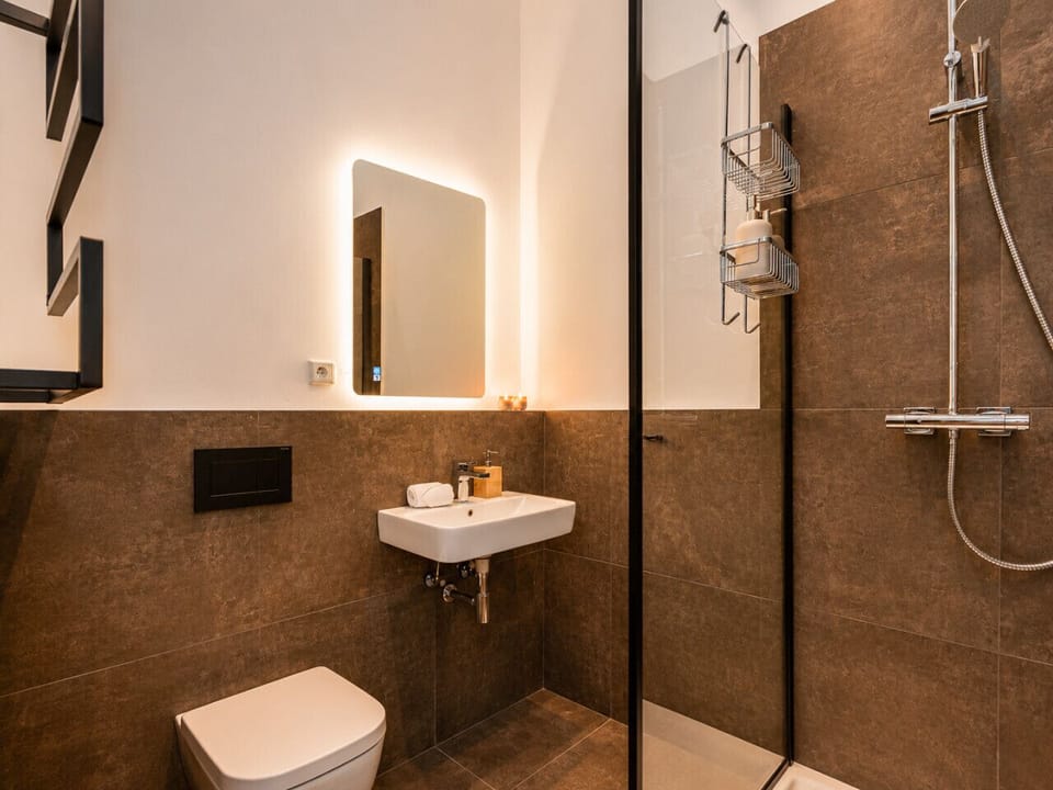 Refresh and unwind in this stylish bathroom with a glass-enclosed walk-in shower, modern vanity, ambient lighting, and premium details that enhance your stay.