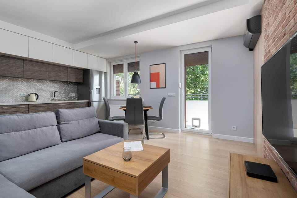 An inviting living room with a TV, sofa, and wooden coffee table. The brick wall gives the room a stylish loft feel.