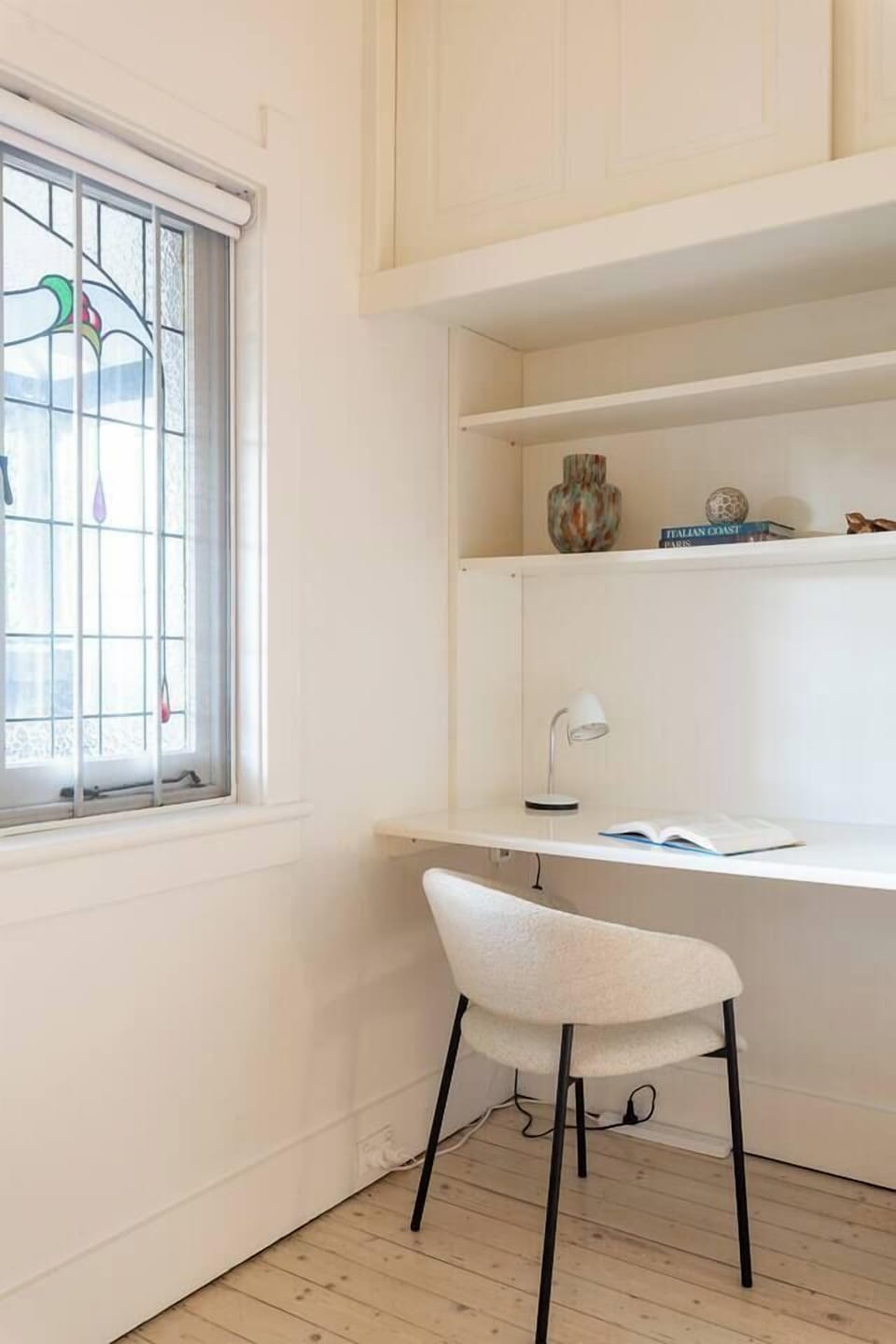 A built-in desk with shelving, a reading lamp, and an elegant chair make the study nook in the second bedroom an ideal spot for quiet work.