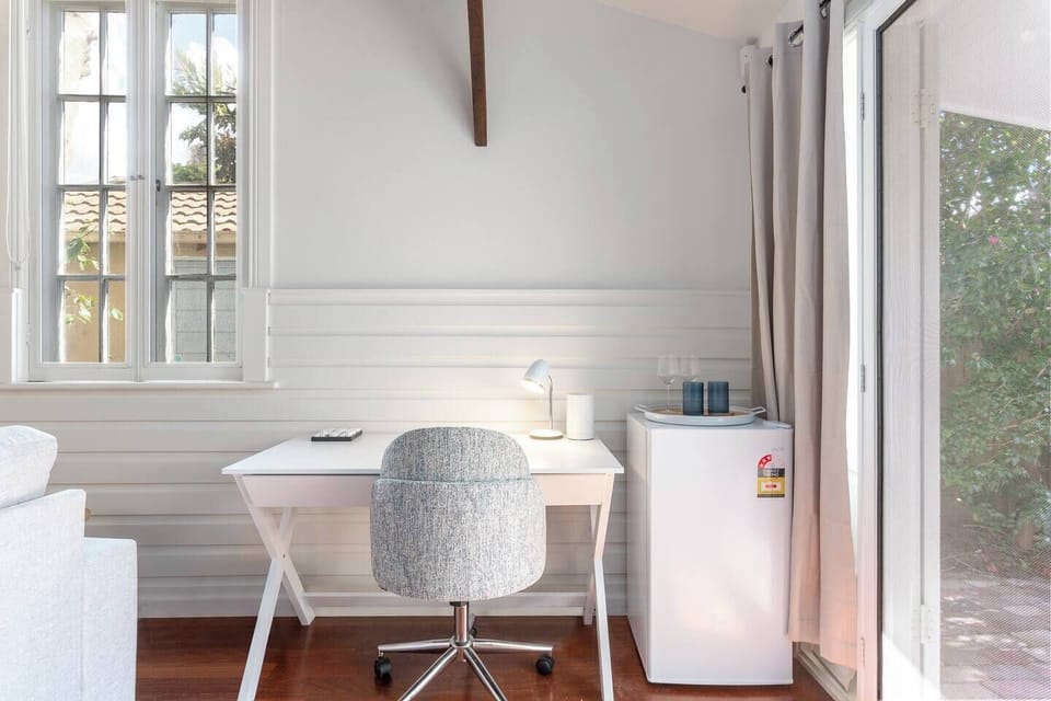 A dedicated workspace with a desk, swivel chair, and reading lamp offers a convenient spot for remote work. A mini fridge sits beside it, perfect for keeping drinks cool.