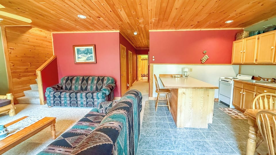 Step into this cozy mountain retreat with warm wood-paneled ceilings and an inviting open-concept layout. The spacious kitchen island is perfect for preparing meals together.