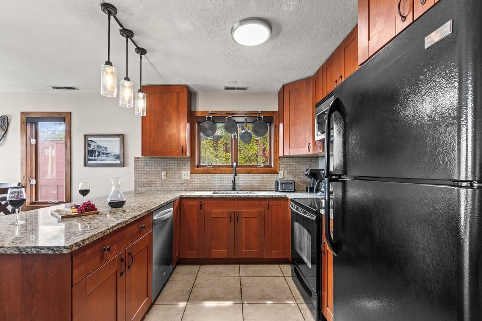 The well-equipped kitchen with black appliances and hardwood cabinets.
