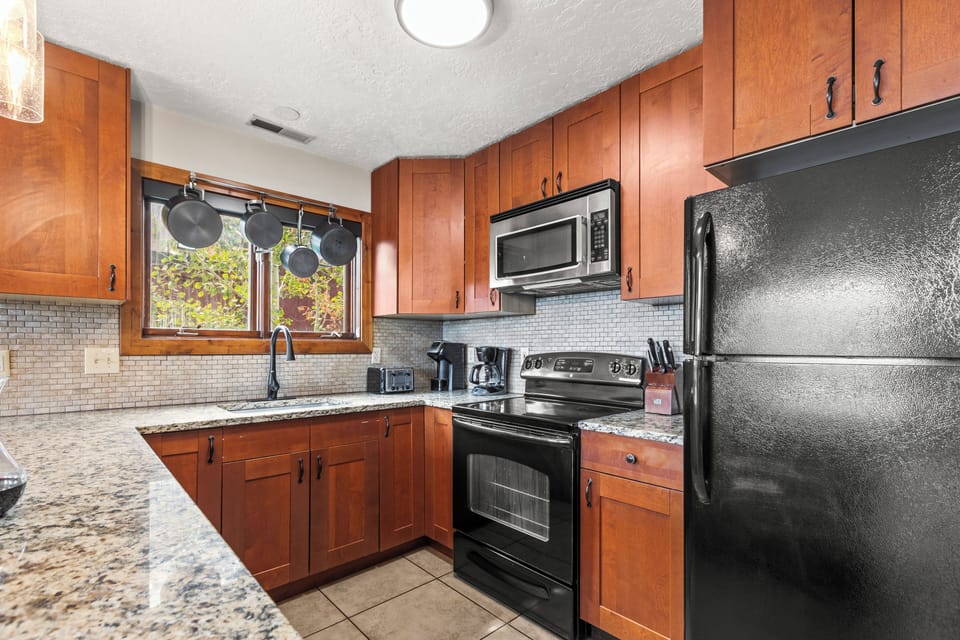 The well-equipped kitchen with black appliances and hardwood cabinets.