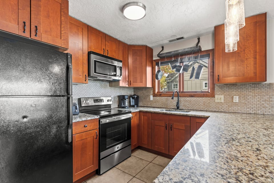The well-equipped kitchen with black appliances and hardwood cabinets.