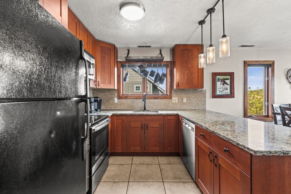 The well-equipped kitchen with black appliances and hardwood cabinets.