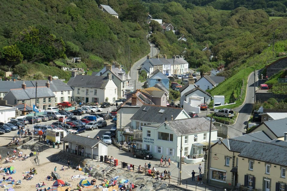 Aerial view of beach and village, busy with people, cafes, pubs and car park
