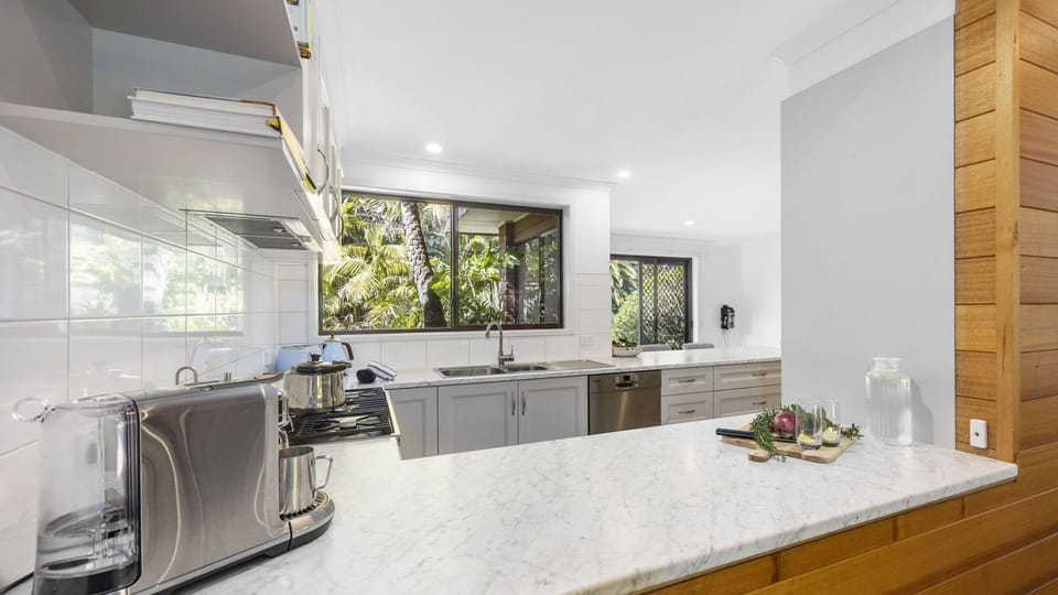 Spacious kitchen featuring modern appliances and a breakfast bench with stools
