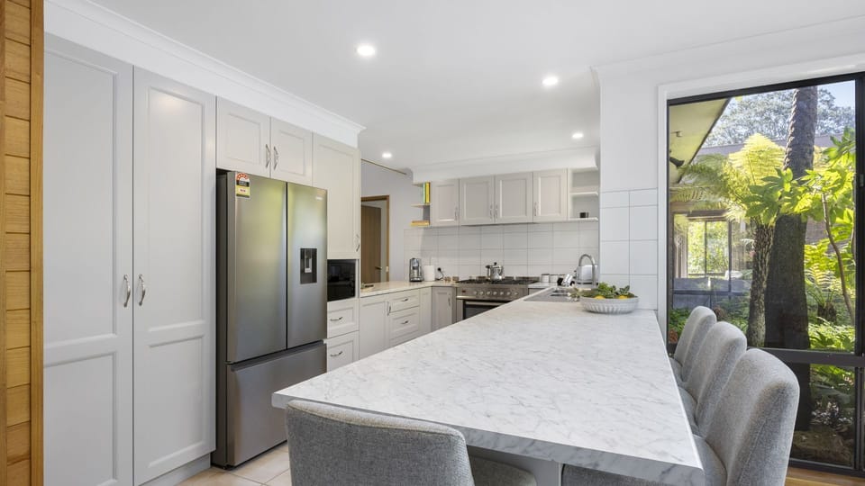 Spacious kitchen featuring modern appliances and a breakfast bench with stools