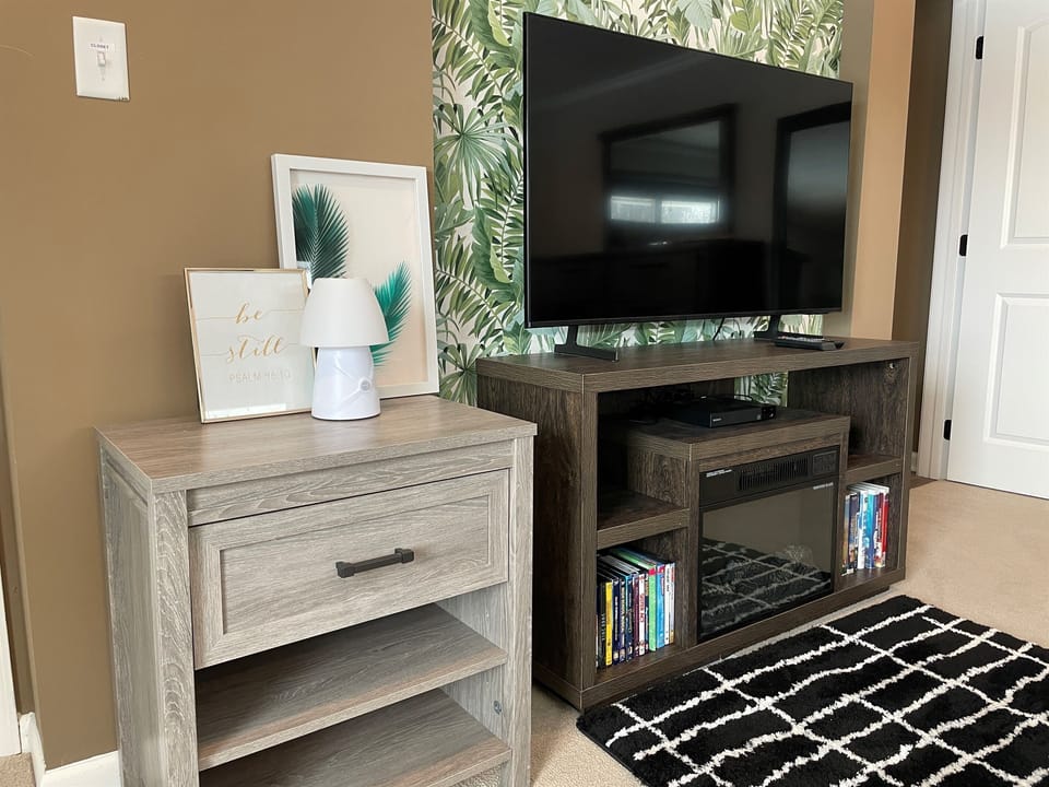 Another angle of the master bedroom showcasing the in-room TV, cozy electric fireplace, and generous closet space.