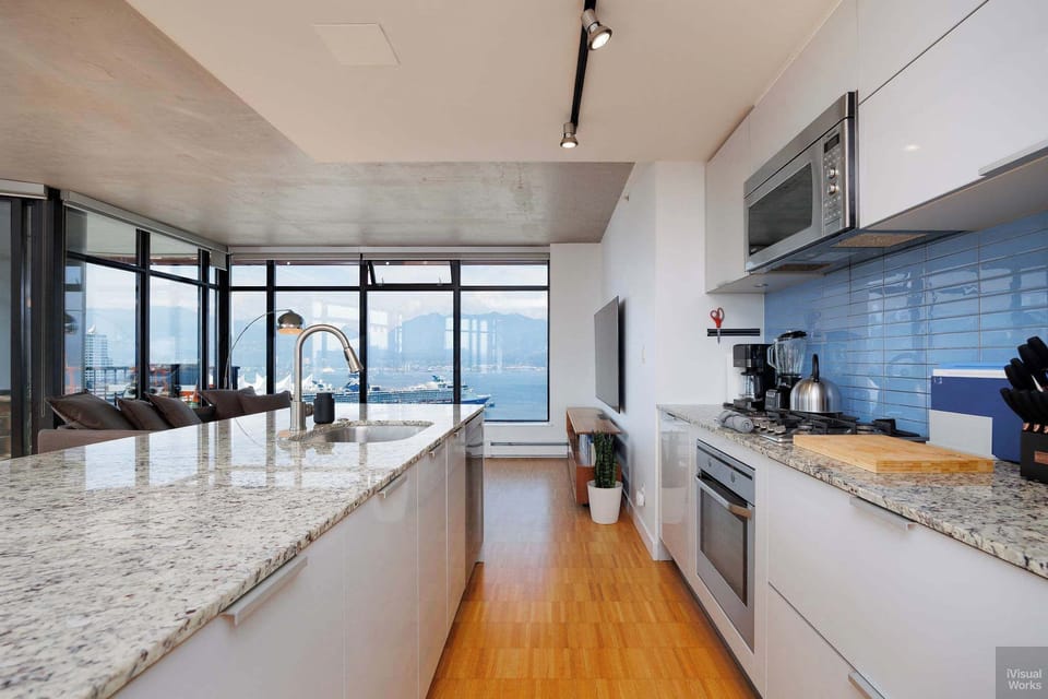 Cook with a view! This modern, fully-equipped kitchen features a large granite countertop island that overlooks the open-concept living area and the beautiful harbor and mountain scenery.