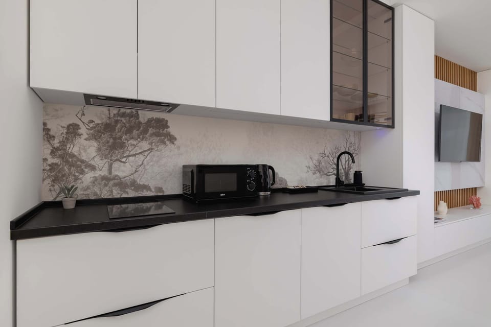 Kitchenette area with modern white cabinets, black countertops, and built-in appliances.
