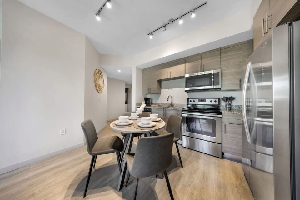 Modern Kitchen with Dining Space- Fully equipped kitchen featuring stainless steel appliances, sleek cabinetry, and a dining table for four—perfect for cooking and enjoying meals together.