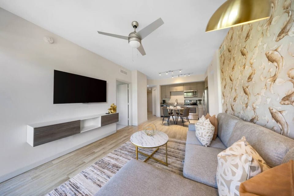 Bright Modern Living Room- Spacious living area with stylish décor, comfy sectional sofa, flat-screen TV, and open layout leading to the kitchen—perfect for relaxing or entertaining.