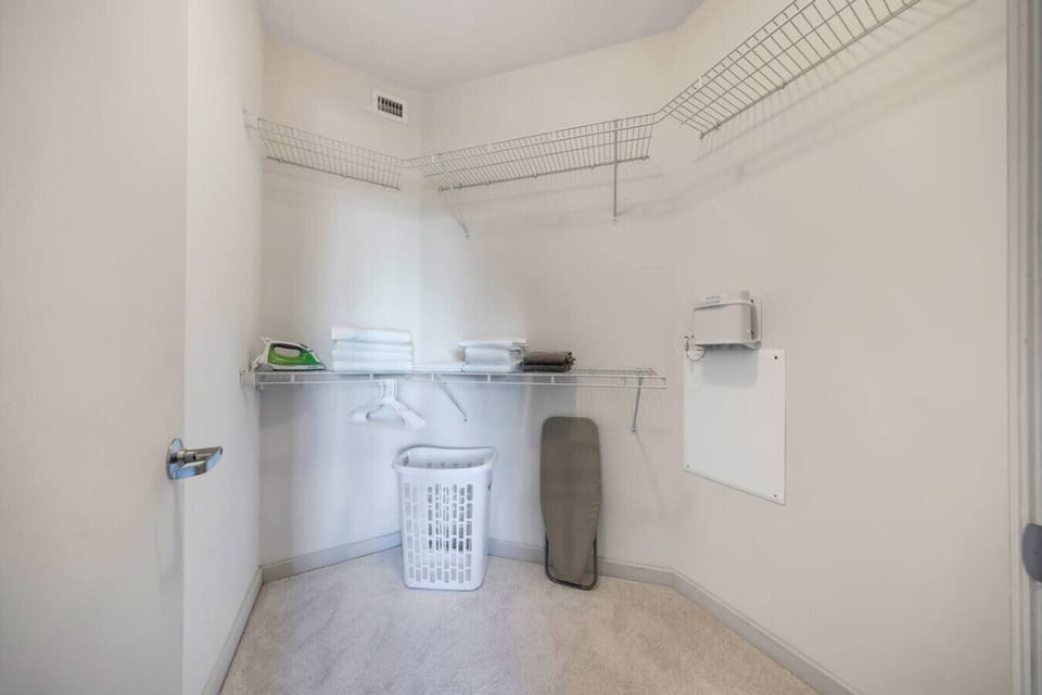 Spacious Walk-In Closet- Large walk-in closet with shelving, hangers, and essentials like towels, ironing board, and laundry basket—perfect for extended stays.