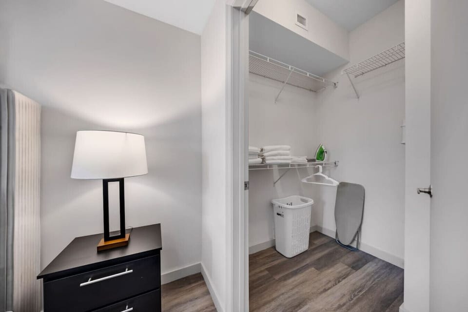 Spacious Walk-In Closet-Organized closet with wire shelving, fresh linens, and storage essentials. Includes laundry basket and ironing board for added convenience during your stay.