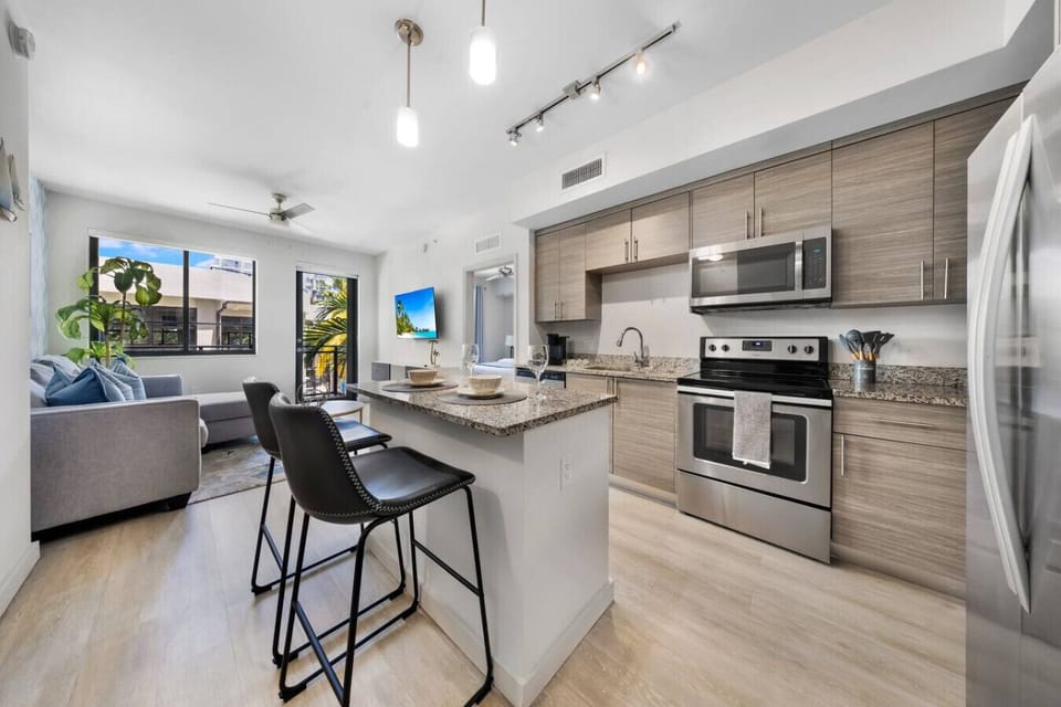 Bright Modern Kitchen-Contemporary kitchen with stainless steel appliances, white cabinetry, and stylish backsplash. Open layout flows into the dining area, perfect for cooking and entertaining.