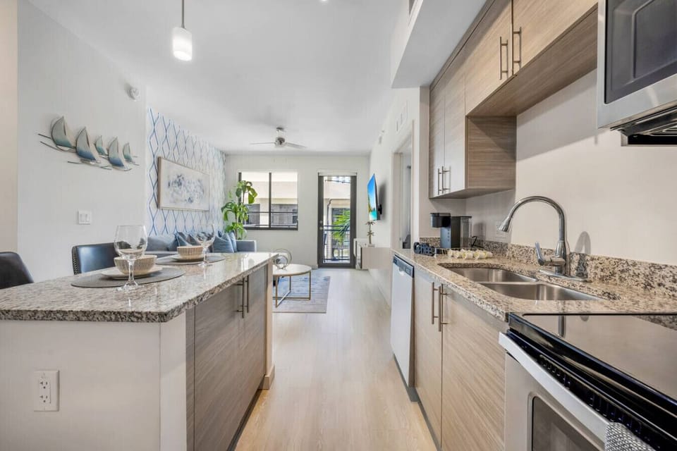 Open-Concept Kitchen-Modern kitchen with stainless steel appliances, white cabinetry, and stylish backsplash. Overlooks the living area with natural light, creating a bright and inviting open layout.