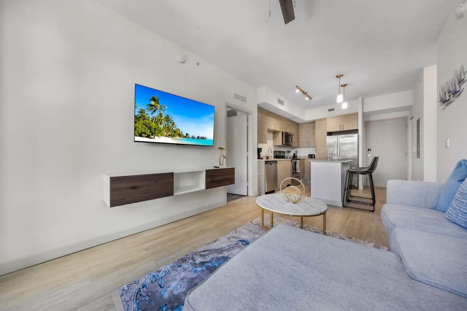 Modern Living Area with Kitchen-Stylish open-concept living space with a cozy sofa, flat-screen TV, and sleek kitchen. Features bright décor, dining island, and a welcoming atmosphere for relaxation or entertaining.