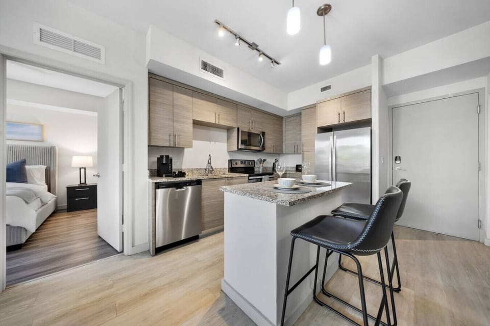 Modern Kitchen with Breakfast Bar-Fully equipped kitchen with stainless steel appliances, granite countertops, and sleek cabinetry. Includes a center island with bar seating for casual dining and convenience.