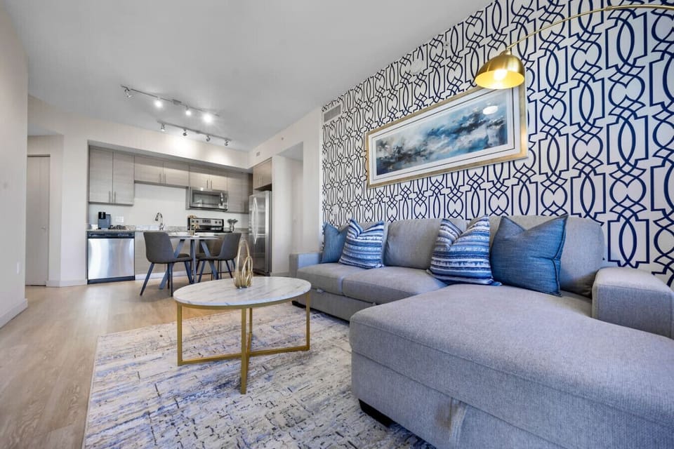 Chic Living Room with Open Kitchen-Stylish living space featuring a sectional sofa, modern décor, and accent lighting. Opens to a fully equipped kitchen and dining area, creating a perfect spot to relax or entertain.