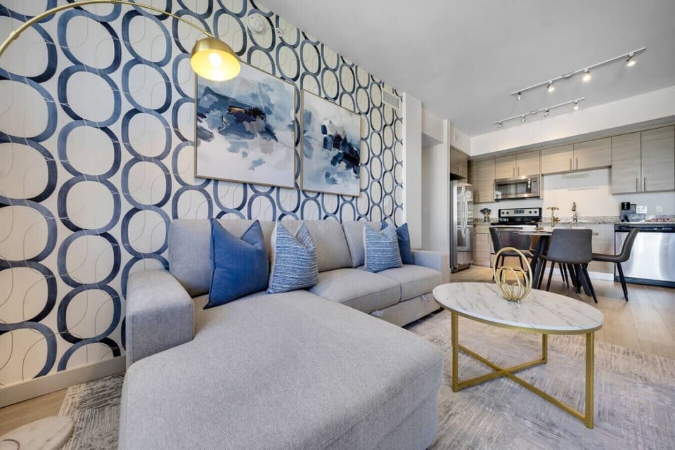 Stylish Living Space-Bright and inviting living area with a modern sectional, bold accent wall, and chic décor. Perfect for relaxing or entertaining with an open layout leading to the kitchen and dining area.