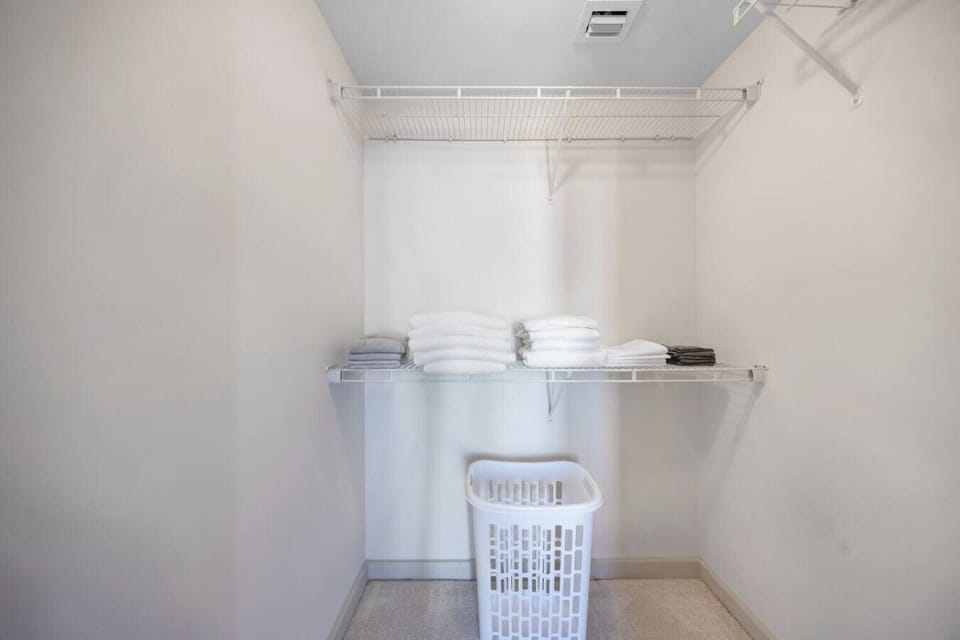 Organized Walk-In Closet-Spacious closet with wire shelving, fresh linens, and essentials neatly arranged. Includes a laundry basket for added convenience during your stay.