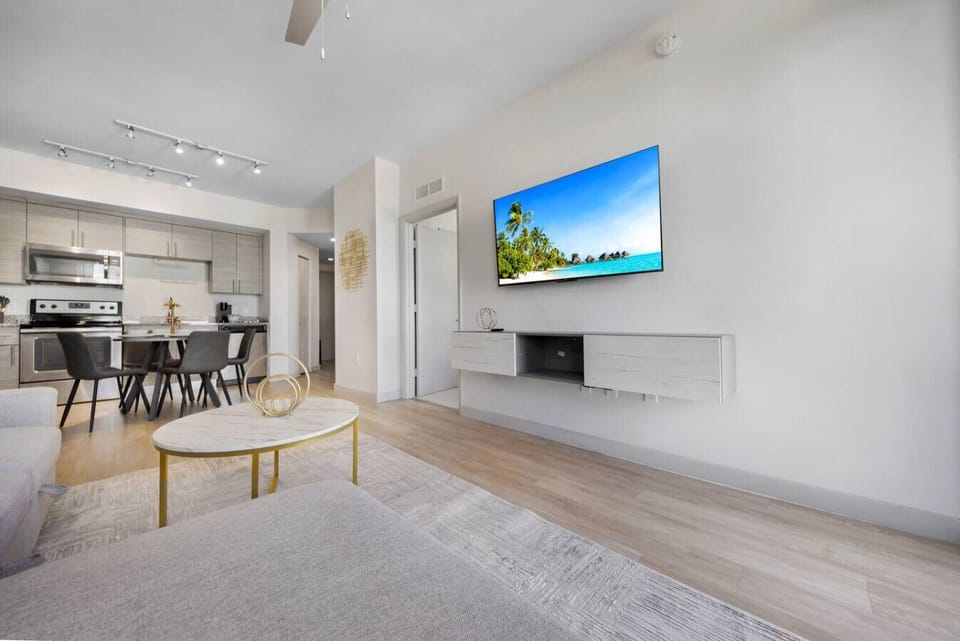 Chic Living Room with Balcony Access-Bright and stylish lounge featuring a modern sofa, bold accent wall, and sleek décor. Large windows and balcony doors fill the space with natural light for a relaxing stay.
