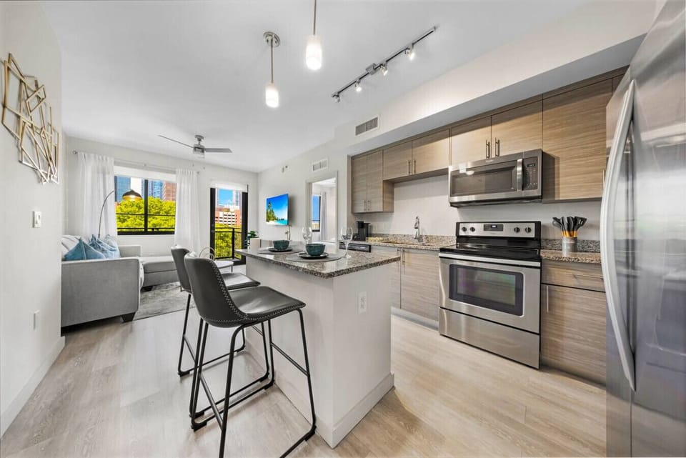 Stylish Kitchen with Island Seating-Modern kitchen with stainless steel appliances, granite island, and bar seating. Open design flows into the living area with large windows and city views.