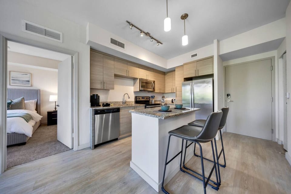 Modern Kitchen with Bedroom Access-Bright kitchen with stainless steel appliances, granite island, and bar seating. Convenient open layout with direct access to the cozy bedroom.