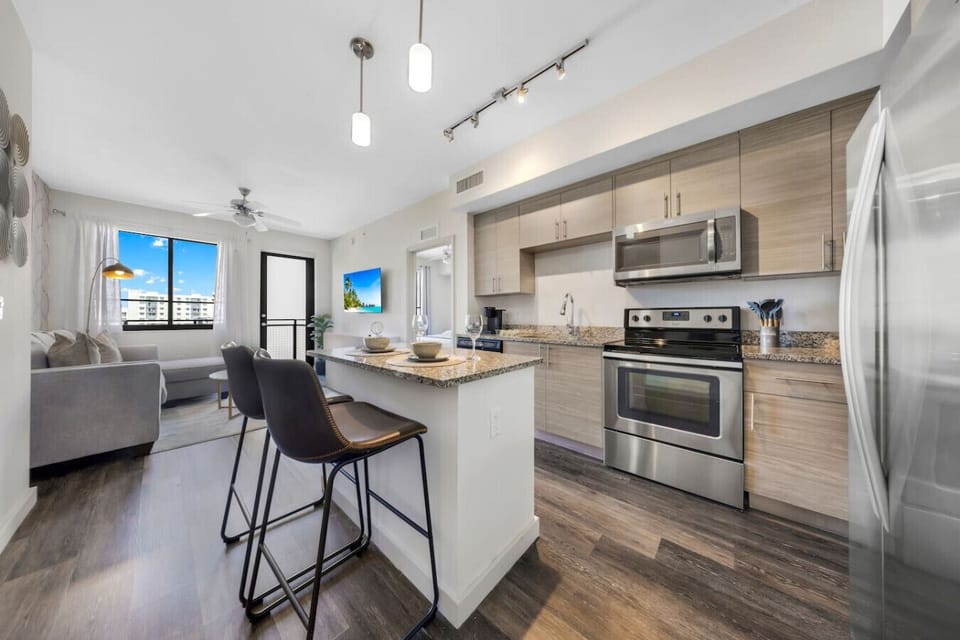 Modern Kitchen with Breakfast Bar- Fully equipped kitchen with stainless steel appliances, sleek cabinetry, and a granite island with bar seating—perfect for casual dining or entertaining.