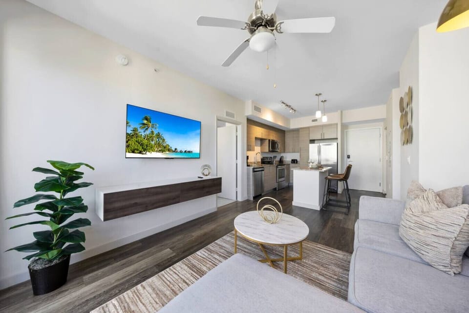 Open-Concept Living & Kitchen- Bright living room with modern décor, cozy seating, and flat-screen TV, seamlessly connected to a stylish kitchen with island seating.