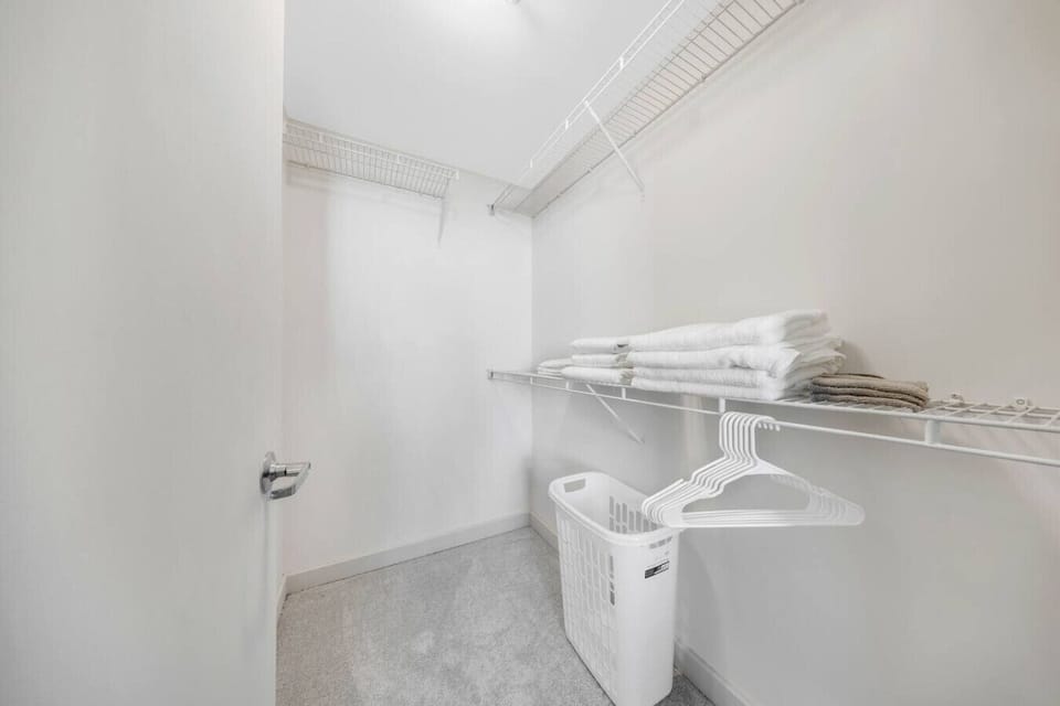 Walk-In Closet with Essentials- Spacious walk-in closet equipped with shelving, hangers, fresh linens, and laundry basket for added convenience during your stay.