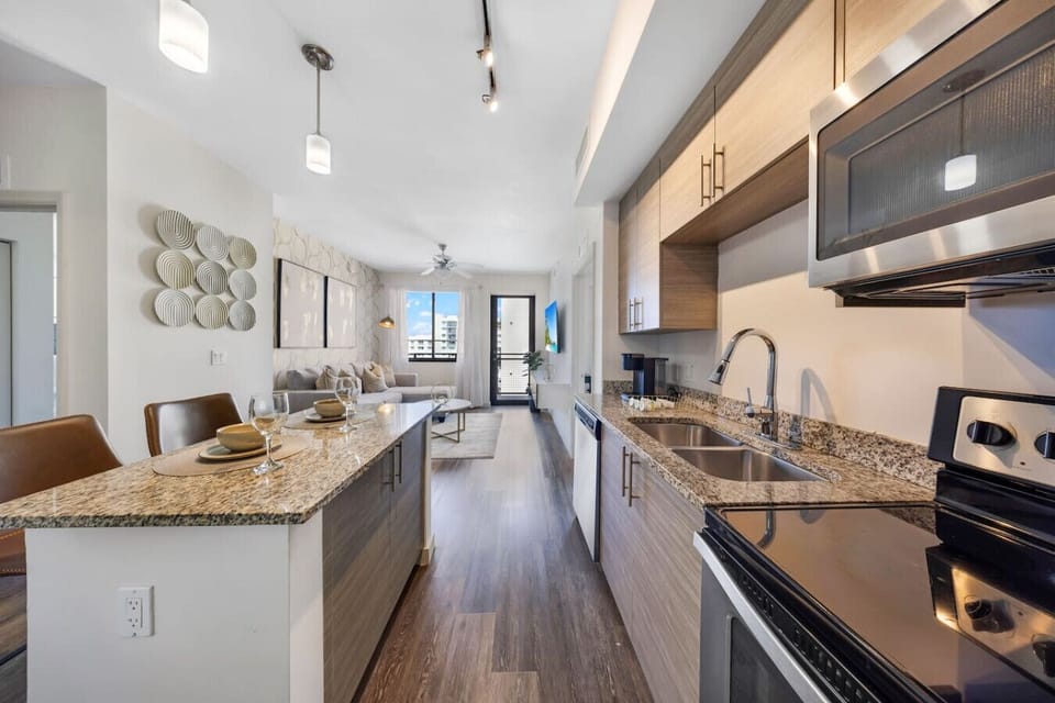 Open Kitchen with Island Seating- Modern kitchen with granite countertops, stainless steel appliances, and a spacious island with bar seating, seamlessly connected to the living area.