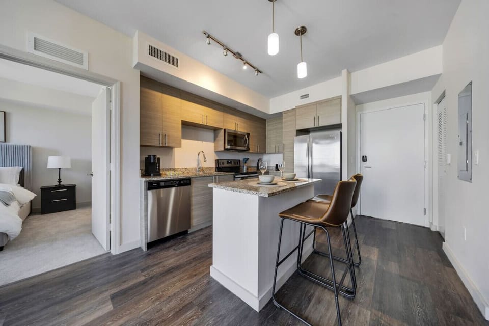 Contemporary Kitchen with Island Seating- Sleek kitchen featuring stainless steel appliances, granite countertops, and a central island with bar seating, conveniently connected to the bedroom.