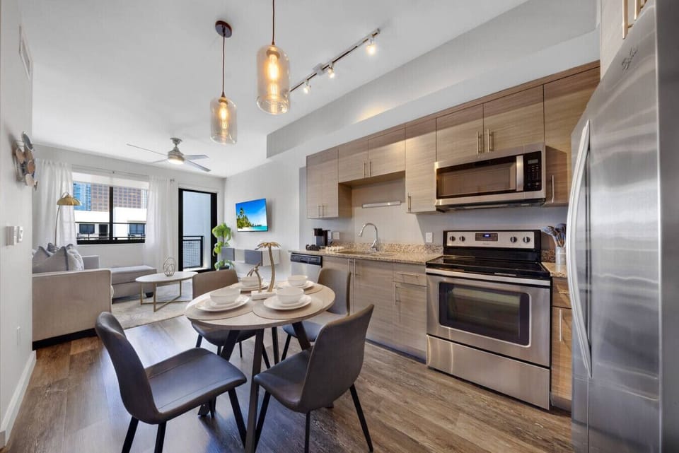 Bright Modern Kitchen-Contemporary kitchen with stainless steel appliances, white cabinetry, and stylish backsplash. Open layout flows into the dining area, perfect for cooking and entertaining.