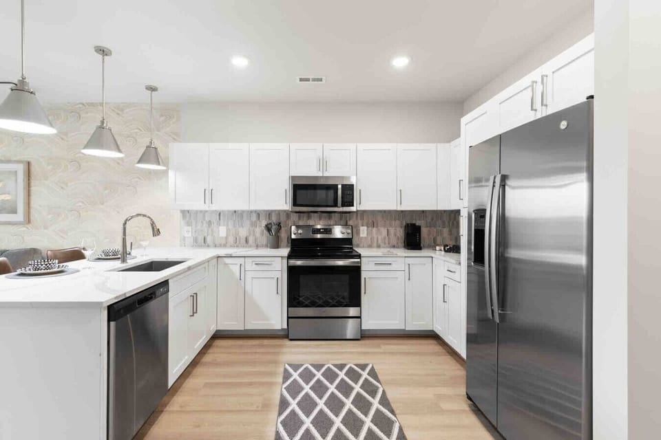 Modern Chef’s Kitchen-Spacious kitchen with sleek white cabinetry, stainless steel appliances, and a large refrigerator. Bright lighting and ample counter space make it perfect for cooking and entertaining.
