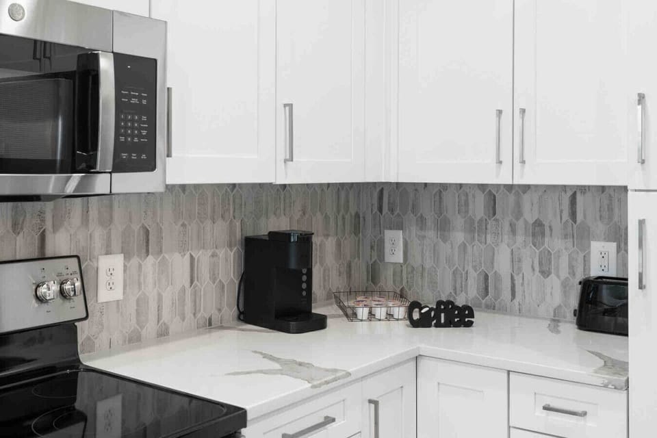 Modern Kitchen Essentials-Sleek kitchen setup with stainless steel appliances, stylish backsplash, and coffee maker with pods ready for guests. Perfect for convenient cooking and a fresh morning start.
