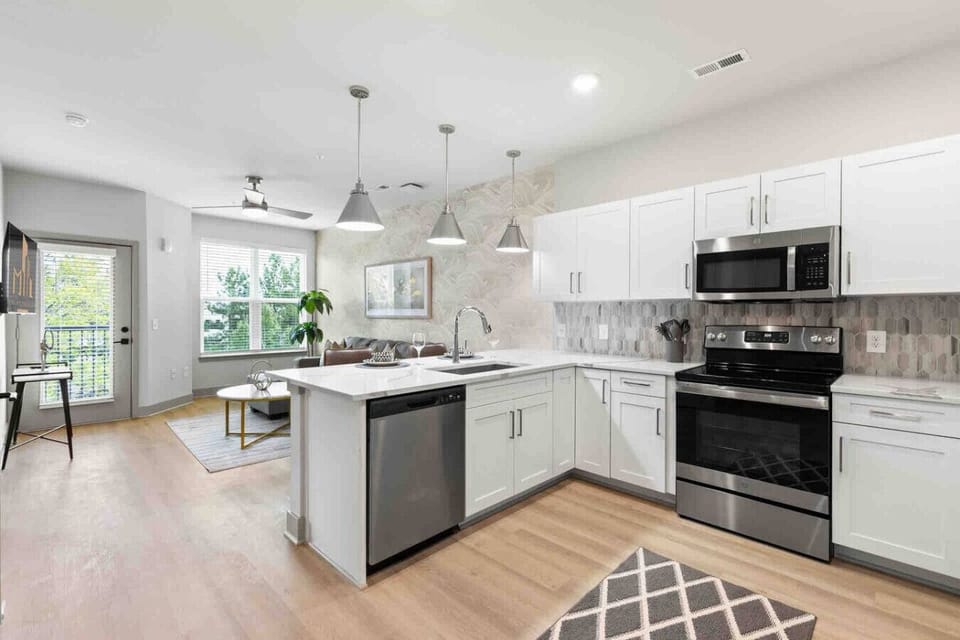 Bright Modern Kitchen-Stylish kitchen with white cabinetry, stainless steel appliances, and a spacious island. Open layout flows into the living area, perfect for cooking and entertaining.