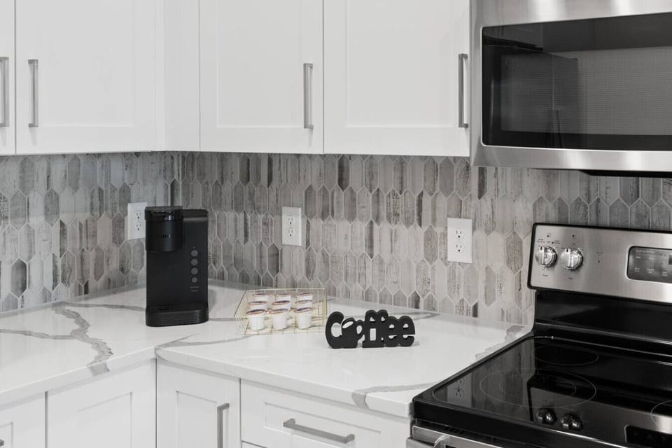Coffee Station in Modern Kitchen-Convenient corner setup with a sleek coffee maker, stylish white cabinetry, and contemporary backsplash. Perfect for starting the day with your favorite brew in a bright, modern space.