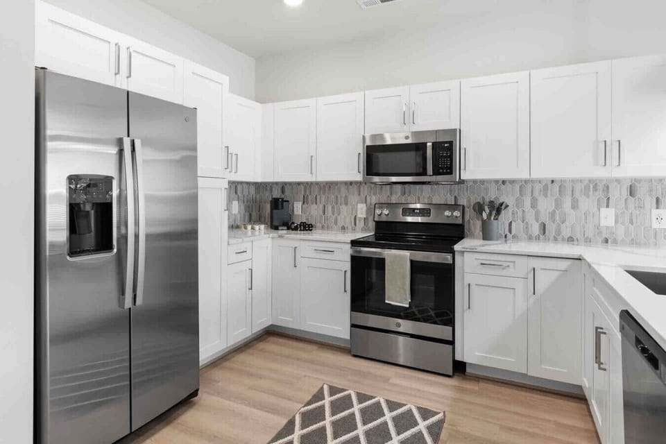 Modern Kitchen with Stainless Appliances-Bright kitchen featuring sleek stainless steel fridge, oven, and microwave, white cabinetry, and stylish backsplash—fully equipped for cooking and dining in comfort.