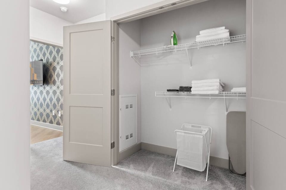 Organized Closet Space-Spacious closet with shelving, fresh linens, iron, and laundry basket. Provides practical storage to keep your stay tidy and convenient.
