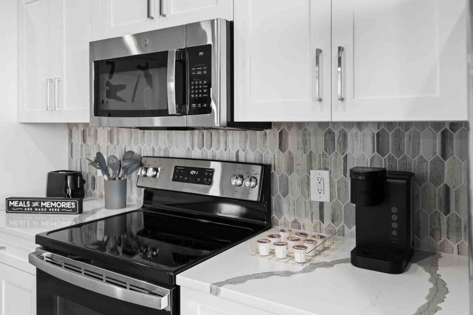 Kitchen Essentials-Modern kitchen setup with stainless steel appliances, stylish backsplash, and a coffee maker for added convenience.