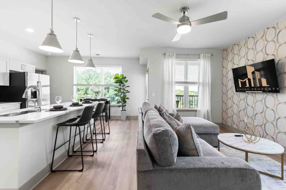 Open Living & Kitchen Space-Modern open-concept layout with a sleek kitchen island, bar seating, and a cozy living area featuring a sectional sofa and mounted TV.