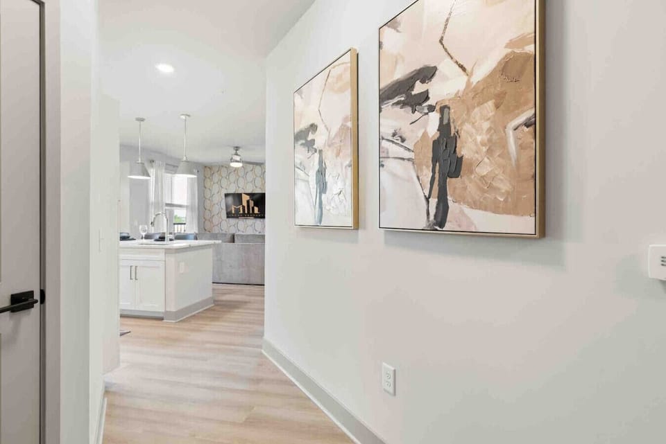 Welcoming Hallway-Modern entry hallway with stylish artwork, light wood flooring, and a bright open view leading into the kitchen and living area for a warm first impression.