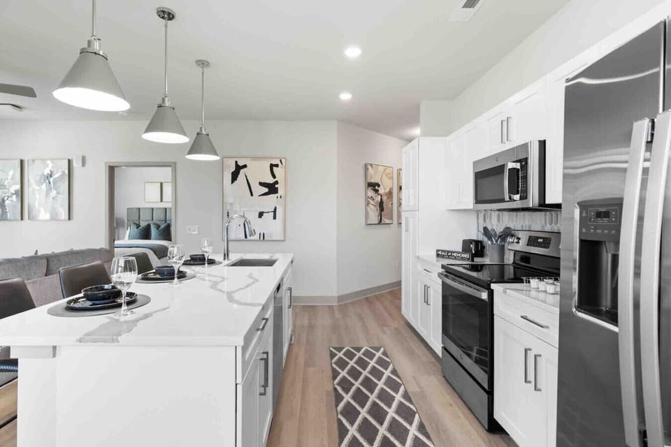 Sleek Modern Kitchen-Spacious kitchen with white cabinetry, stainless steel appliances, and a large island with sink and seating—designed for both cooking and entertaining.